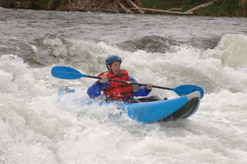 boy takes on waves in kayak